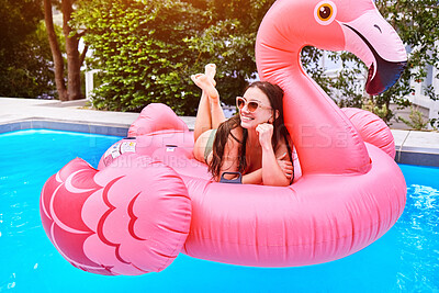 Buy stock photo Happy girl, relax and pool with flamingo for floating, swim or summer time at holiday resort. Female person, smile or lying on pink floaty in water for aqua party, relaxation or outdoor vacation