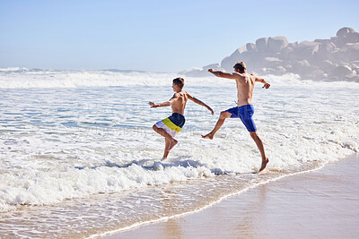 Buy stock photo Father, boy and running at beach for vacation, bonding or love with water splash, waves or kick in nature. Dad, child and playful for care, holiday or people with family in sunshine by ocean in Spain