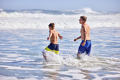 Buy stock photo Father, boy and playful at beach with waves, bonding or love in splash, vacation and together in nature. Dad, child and running with care, holiday or people with family in sunshine by ocean in Spain