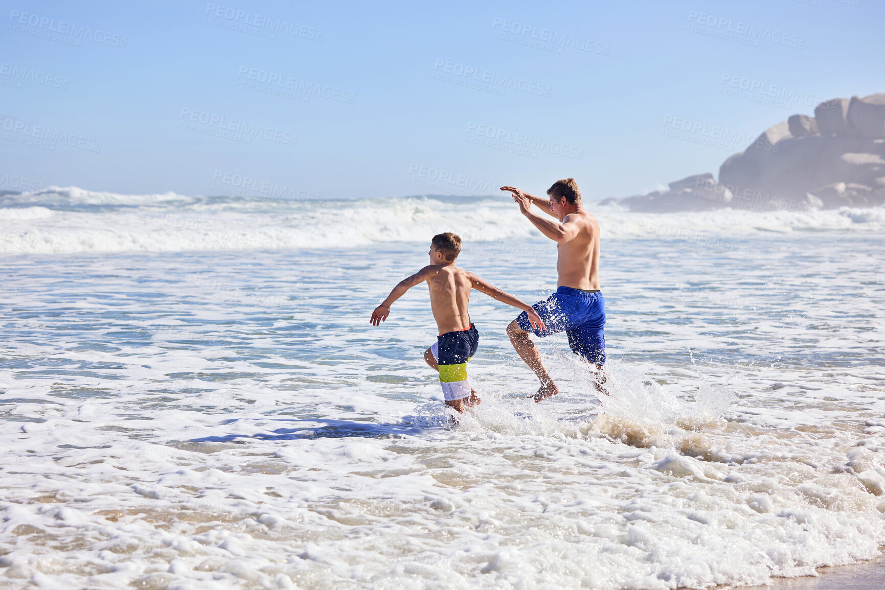 Buy stock photo Father, son and running at beach with waves, bonding or love in summer, vacation and together in nature. Dad, child and playful with care, holiday or people with family in sunshine by ocean in Spain