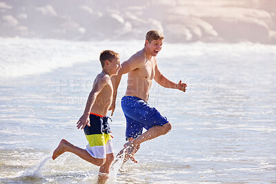 Buy stock photo Dad, son and running at beach with waves, bonding or love in splash, vacation and together in nature. Father, child and playful with care, holiday or people with family in sunshine by ocean in Spain