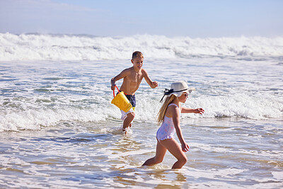 Buy stock photo Children, beach or running with toys in water for playing with fun activity, summer holiday or development. Kid, siblings or swimwear at sea with tropical adventure, family vacation or plastic bucket