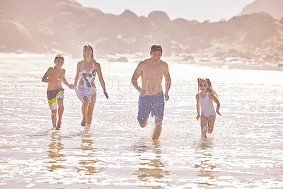 Buy stock photo Parents, children and running at sea, beach and vacation with love, summer and happy in nature. Father, mother and kids with splash, holiday and outdoor with family in sunshine by ocean in Spain