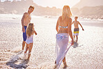 Parents, children and walking at sunset, beach and vacation with love, summer and back in nature. Father, mother and kids with connection, holiday and outdoor for family in sunshine by ocean in Spain