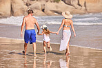 Walk, child and parents holding hands on beach for fun, travel holiday and bonding together on tropical adventure. Mom, dad and girl on family vacation with ocean, support and island summer from back