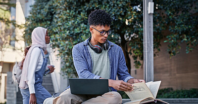 Buy stock photo Reading book, college student and man on laptop for IT course, studying or research on internet. Education, outdoor or person with headphones, notes or technology for knowledge, university or website