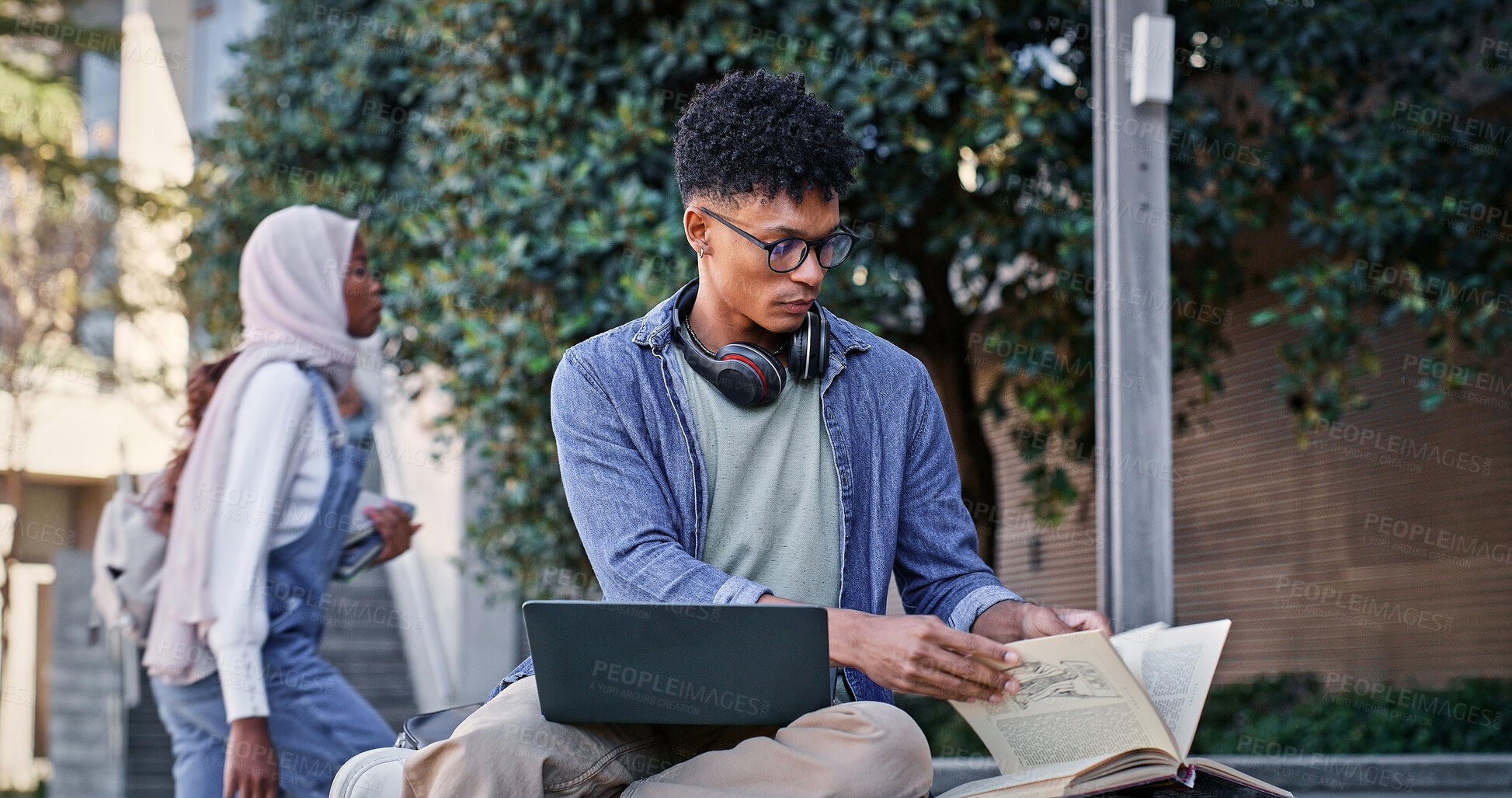 Buy stock photo Reading book, college student and man on laptop for IT course, studying or research on internet. Education, outdoor or person with headphones, notes or technology for knowledge, university or website