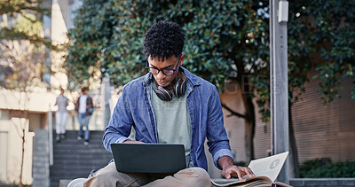 Buy stock photo Reading book, outdoor or college student on laptop for IT course, studying or research on internet. Education, campus or man with headphones, notes or technology for knowledge, university or website