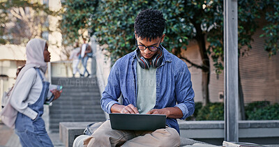 Buy stock photo Student, glasses and typing with laptop outdoor for university project, research and information of education. Man, headphones and and digital writing for online learning, exam results and studying