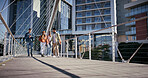 City, people and friends walking on bridge together with smile, buildings and conversation. University, scholarship and happy group of gen z students chat on morning commute to urban college campus