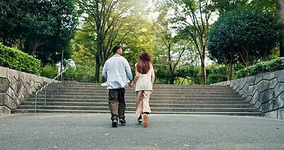 Buy stock photo Couple, holding hands and walking in urban park of Japan, back and bonding on honeymoon vacation. People, security and outdoor support on holiday in nature, travel together and explore relationship