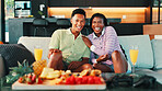 Happy, platter and couple on sofa in home watching tv for movie, film or show together for date. Snacks, mimosas and man with woman for relaxing, laughing and streaming series in living room in house