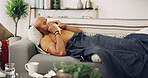 Living room, sneeze and sick man with tissue, sofa and allergies for sinus, season and infection. Couch, blanket and symptoms with fever rest, runny nose and health of person with virus in house