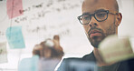 Writing, planning and business man by glass for brainstorming, discussion and ideas in office. Creative company, startup and person with sticky notes for strategy, research and schedule for project
