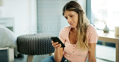 Buy stock photo Woman, mobile and smile on floor with relax, social media and message in texting app. Female person, phone and online in home living room for ebook reading, video and gossip conversation on contact
