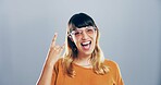 Portrait, edgy or happy woman with rock hand gesture in studio for expression or space on gray background. Culture, cool female rocker and crazy woman with devil horn sign, funky emoji or punk symbol