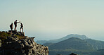 Hiking, group and friends on mountain, high five and scenery in nature, space and adventure for tourists. Celebration, traveller and people with gesture for holiday, view and success for backpacker
