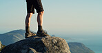 Person, legs and hiker with blue sky on mountain for adventure, trekking journey or fitness in nature. Shoes, feet or rock cliff with peek or view for hiking trail, travel or sightseeing destination