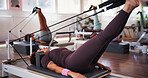Pilates, exercise and women with machine in class with reformer for training, workout and mobility. Fitness, gym and people with equipment for stretching legs for wellness, health and challenge