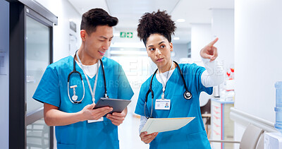 Buy stock photo Doctors, man and woman in hallway with documents, tablet and point for direction, guide and feedback. People, team and happy with digital touchscreen, app and review with medical solution at hospital