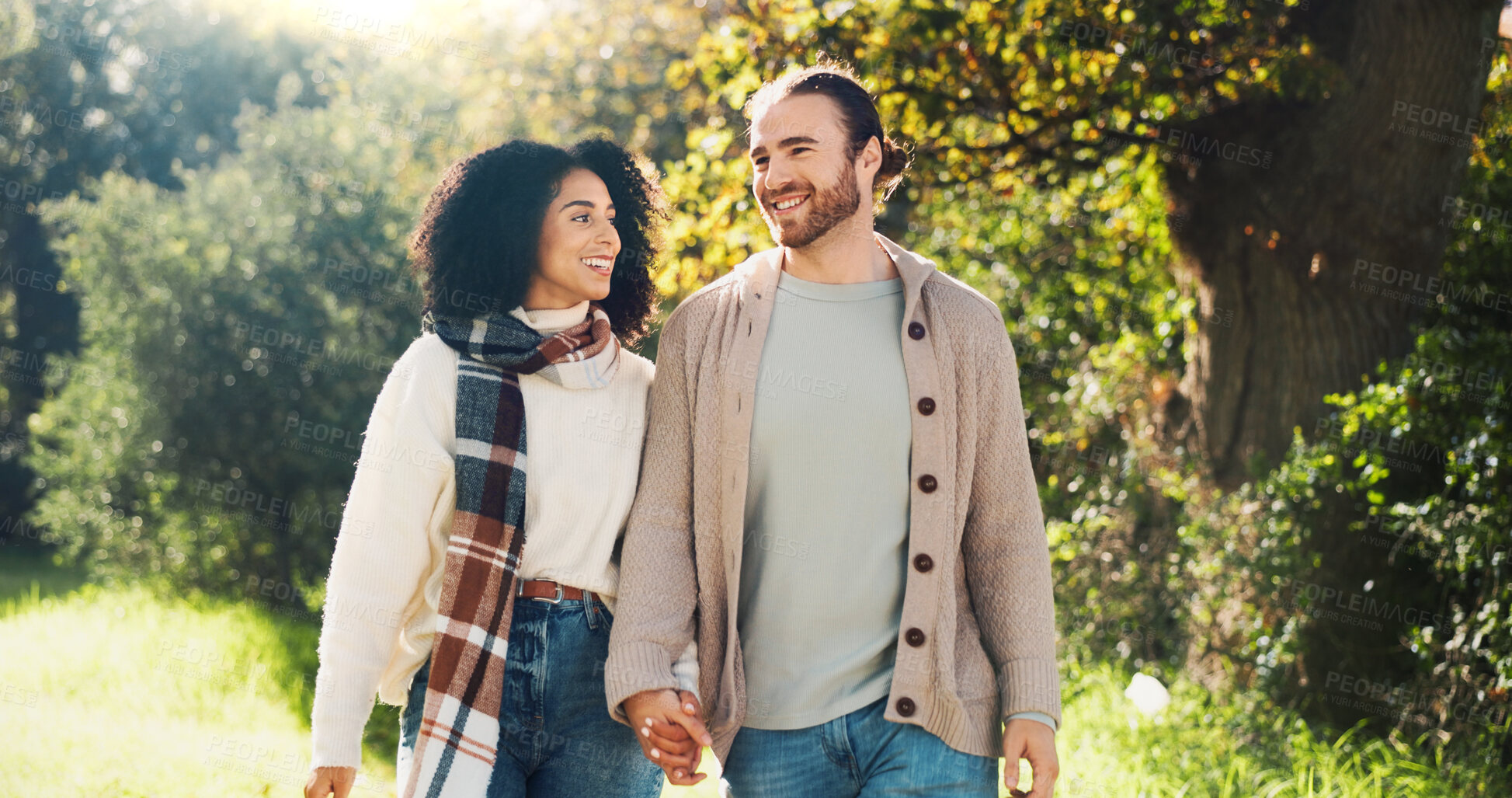 Buy stock photo Outdoor, holding hands and couple on walk, nature and people with smile on date, romance and break. Park, man and woman in relationship, love and happy for interracial marriage, travel or together