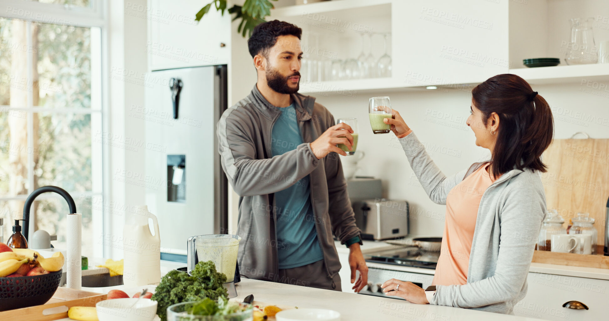 Buy stock photo Cheers, diet and couple with smoothie in kitchen at home for wellness, health and nutrition snack. Love, happy and man with woman for toast with green juice for vitamins or hydration in house.