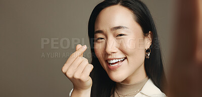 Buy stock photo Woman, selfie and heart fingers in studio, smile and portrait with love, emoji and mockup space by background. Influencer, girl and excited with symbol, gesture or happy on social media in Cambodia