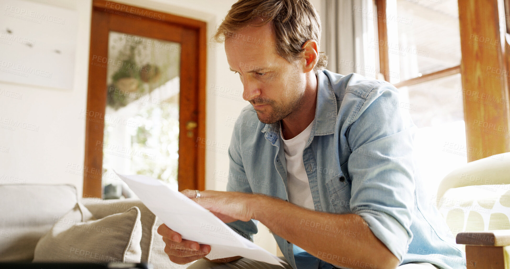Buy stock photo Report, reading and man in living room planning for debt, mortgage or tax payments in home. Paperwork, invoicing and male person with credit application, savings or monthly budget in apartment.