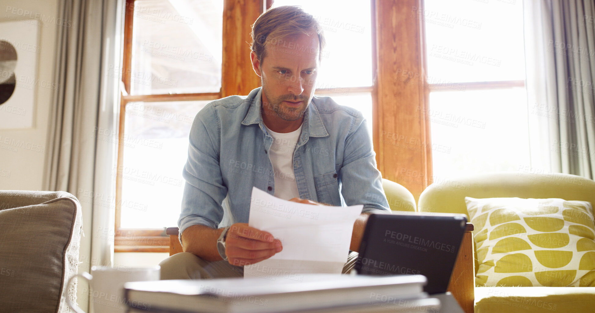Buy stock photo Documents, tablet and man in living room planning for debt, mortgage or tax payments in home. Paperwork, digital technology and male person with credit application, savings or monthly budget in house