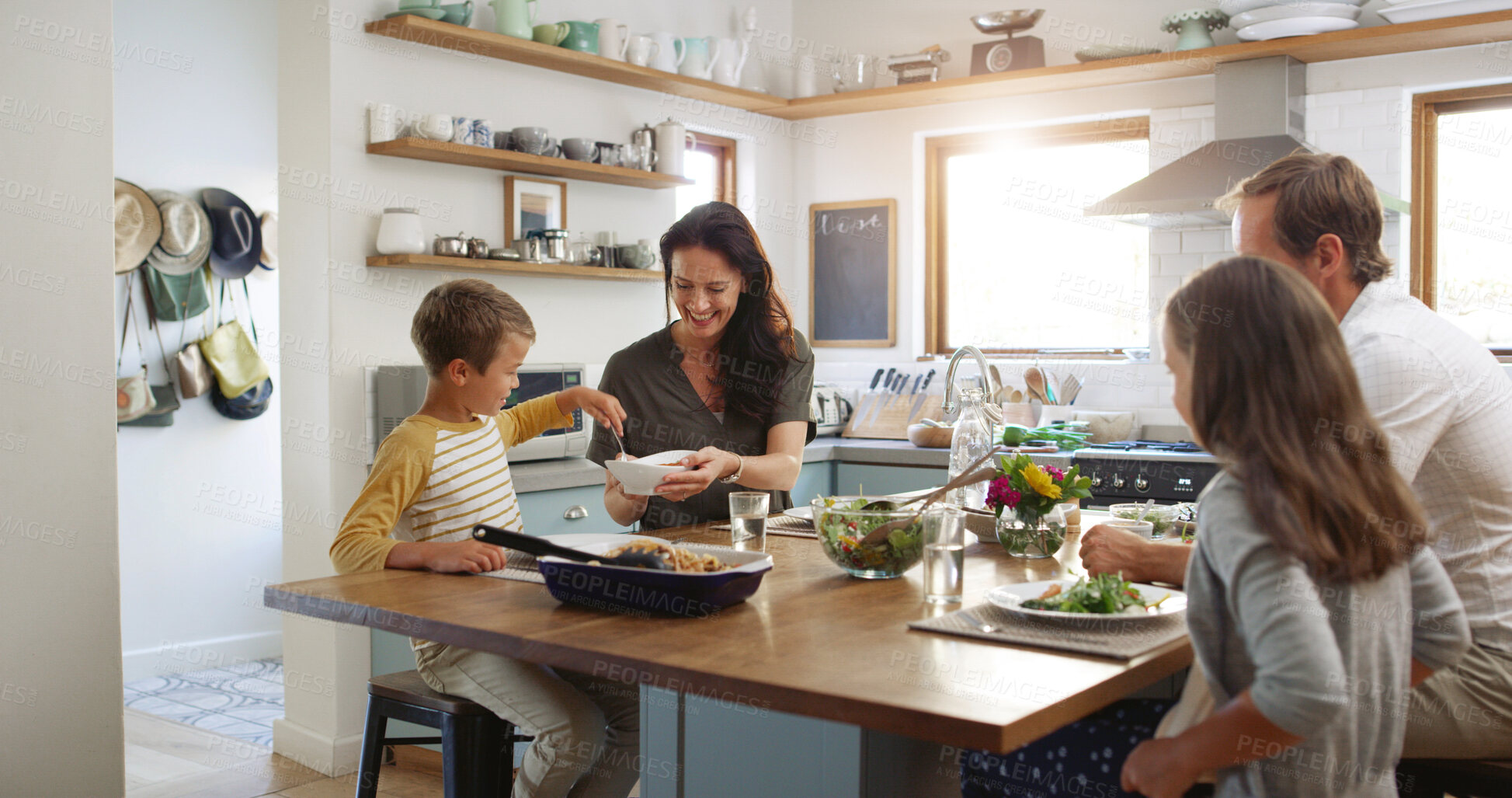 Buy stock photo Smile, lunch and serving with family at kitchen table for help, bonding and health salad. Food, support and happiness with parents and children eating at home for love, wellness and relax together
