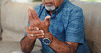 Senior, man and hands with wrist pain in home for carpal tunnel syndrome, arthritis or muscle discomfort. Elderly person, injury and massage joint ache on sofa with osteoarthritis, strain or fracture