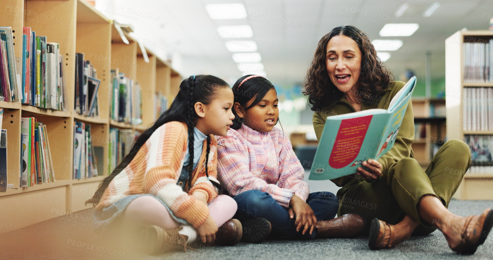 Buy stock photo Girl, teacher and book with reading at library for development, learning or study with guide. School kids, storytelling and woman with help on floor, education and language for knowledge at academy