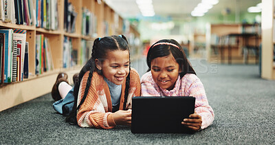 Buy stock photo Students, library and girls on floor, tablet and online learning with education, smile and relax. Happy kids, children and friends on ground, tech or storytelling with ebook, break and knowledge
