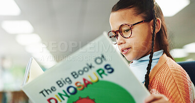 Buy stock photo Girl, child and education with reading book at library with literacy, learning and glasses for dinosaur story. School kid, geek and scholarship for language, knowledge and development at academy
