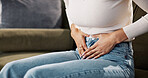 Home, woman and hands on tummy for pain, menstrual cycle and endometriosis on sofa in living room. House, female person and closeup with stomach ache for constipation, gastro crisis and period cramps