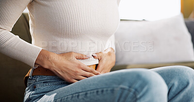 Buy stock photo Home, woman and hands on stomach for pain, menstrual cycle and endometriosis on sofa in living room. House, female person and closeup with abdomen ache for constipation, gastro crisis or period cramp
