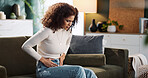 Couch, woman and hands on stomach for pain, menstrual cycle or endometriosis in lounge at home. House, female person or sick with abdomen ache for constipation, gastro crisis or period cramps on sofa
