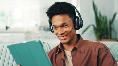Buy stock photo Headphones, tablet and man on sofa in house watching movie, film, or video online. Happy, relax and male person with digital technology and audio tech for streaming app with series in apartment.