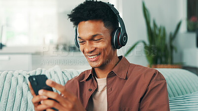 Buy stock photo Headphones, cellphone and man on sofa in home listening to music, album or playlist for review. Happy, relax and male person with phone and audio tech for streaming app with podcast in apartment.
