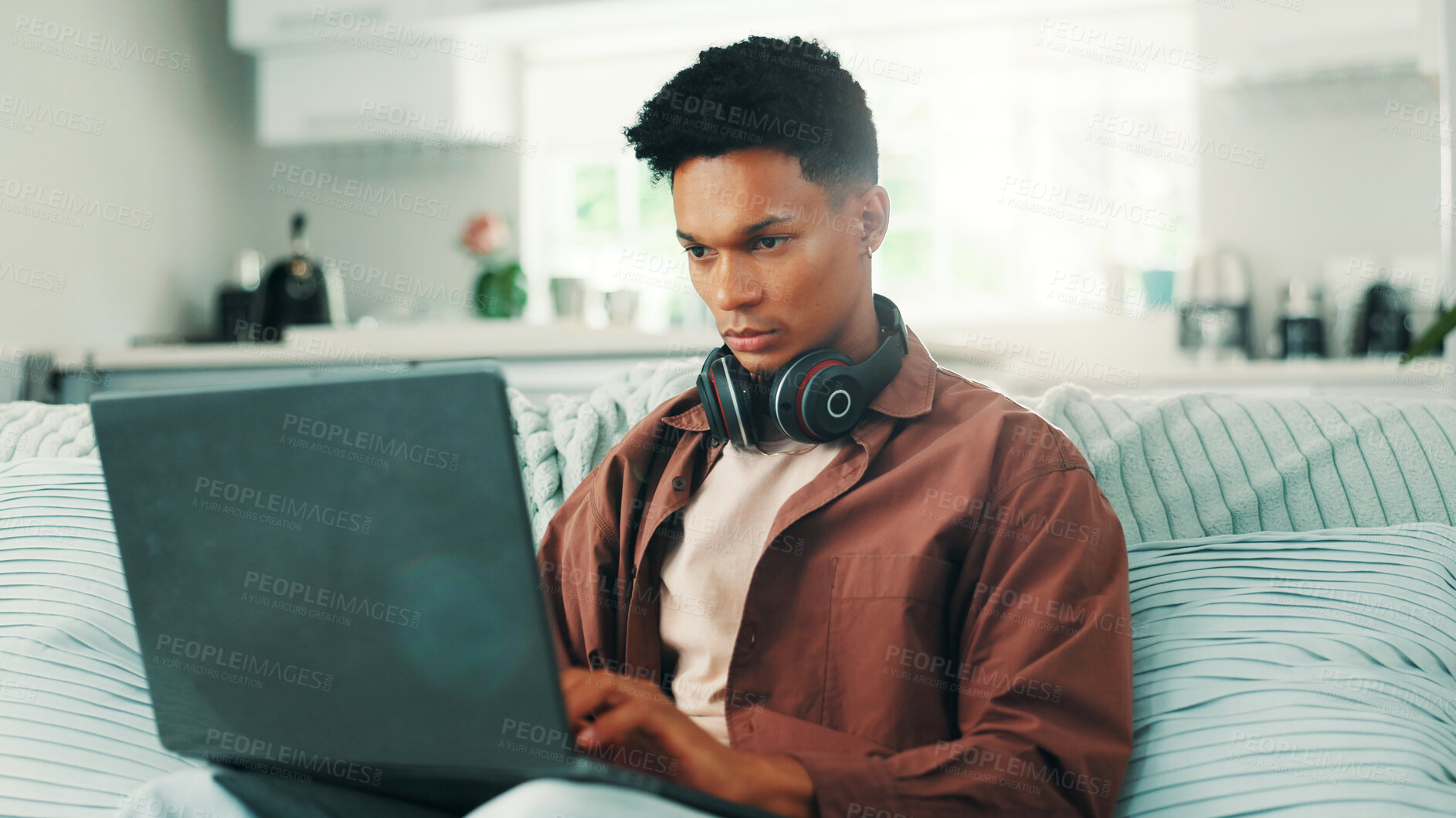 Buy stock photo Break, headphones and laptop with man on sofa in living room of home for weekend browsing. Computer, relax and typing with person in apartment for blogging, online research or streaming content