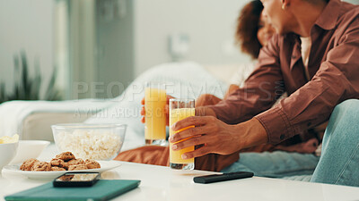 Buy stock photo Hands, watching tv and couple with juice on sofa, care and bonding with love, date or relax in home. People, together and glass for drink with snack for streaming, movie or film on couch at apartment
