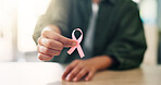 Pink ribbon, hope and hands of woman at home for breast cancer awareness, support and healthcare. Kindness, survivor and oncology campaign with closeup of person and for charity and prevention