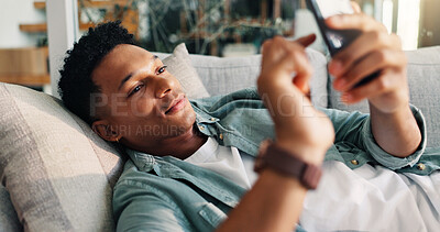 Buy stock photo Man, relax and scroll with phone on sofa for weekend break, dating site chat and app download. Smile, person and rest with smartphone in home with online subscription, social media post or web search