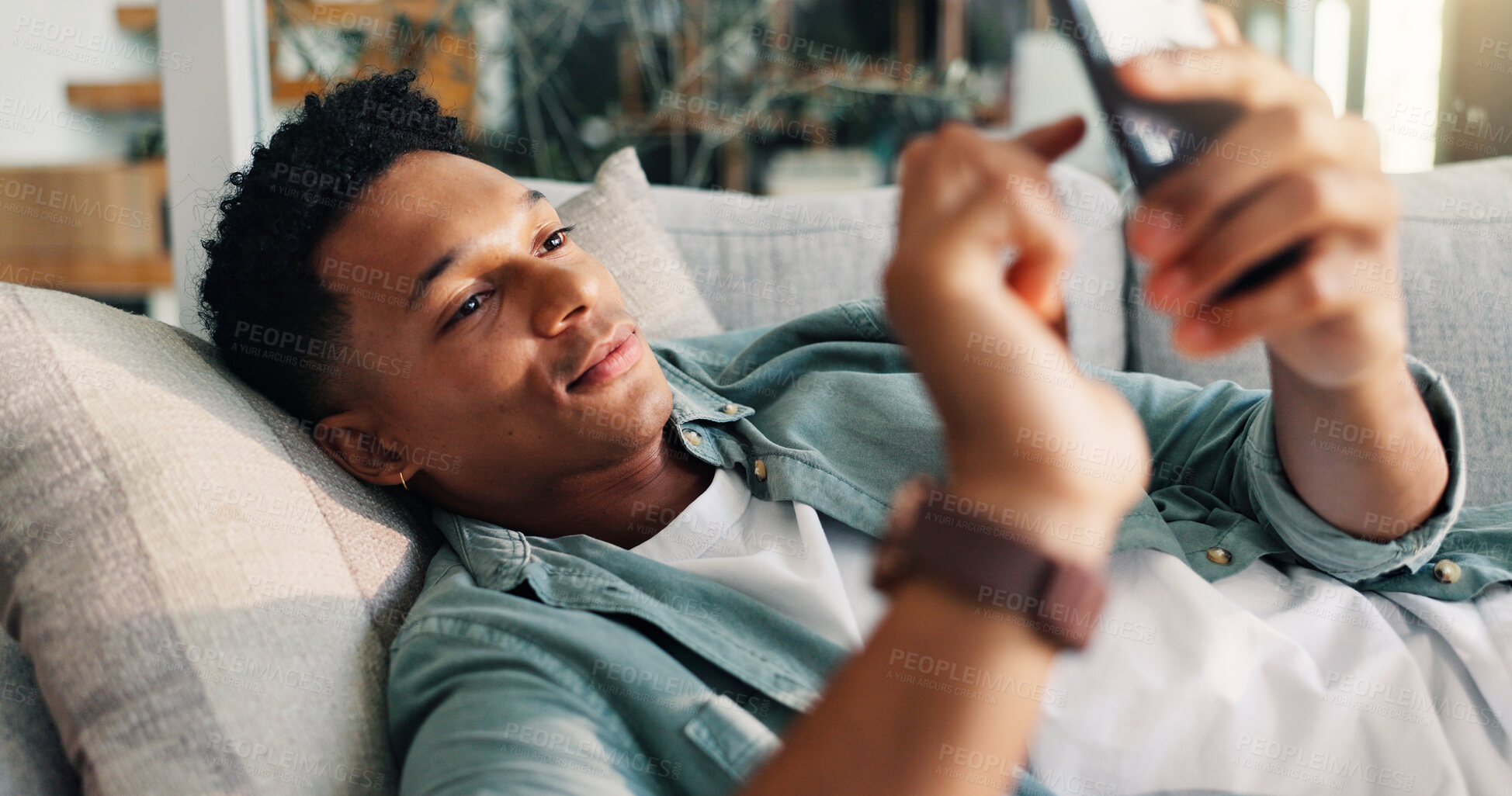 Buy stock photo Man, relax and scroll with phone on sofa for weekend break, dating site chat and app download. Smile, person and rest with smartphone in home with online subscription, social media post or web search