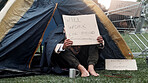 Person, homeless and cardboard for begging with cup, poverty and ask for job, change and food at park. Feet, outdoor and poster for donation, care and hungry on ground with hope for work opportunity