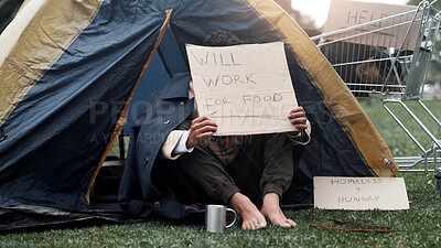 Buy stock photo Person, homeless and cardboard for begging with cup, poverty and ask for job, change and food at park. Feet, outdoor and poster for donation, care and hungry on ground with hope for work opportunity