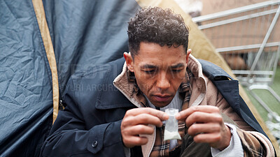Buy stock photo Man, poverty and homeless with drugs in bag at park, package and thinking with illegal product by tent. Person, narcotic substance and chemical for craving, crime and poor with stress in Brazil