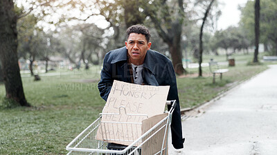 Buy stock photo Homeless, person and begging with cardboard in shopping cart for financial aid, economic hardship and poverty. Walking, beggar and trolley in street with hungry sign, desperate and social injustice
