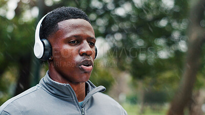 Buy stock photo Runner, exercise and man with headphones in rain for training music, breathing and cardio challenge with sound. Wet, black person and listening to podcast for fitness, jog and workout with playlist