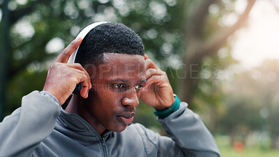 Buy stock photo Fitness, man and tired with headphones at park for running break, marathon training and cardio workout with sweating. Black person, rest and listening to podcast for exercise, morning jog and fatigue